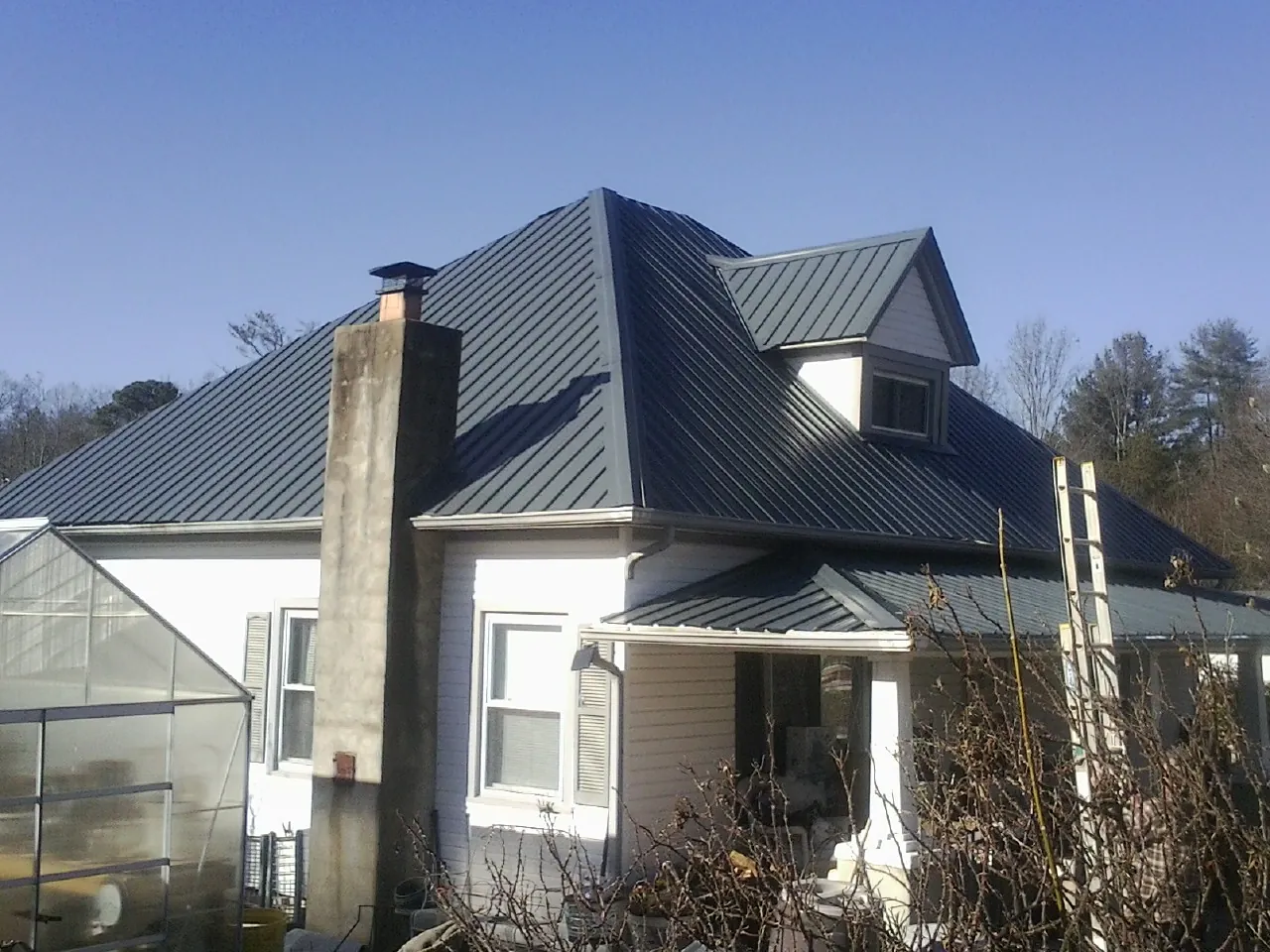 Dark blue standing seam metal roof on a white farmhouse with dormer — Slate & Tile Roof Repair by Roofing Brothers in Blytheville