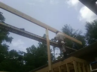 Carpenter setting a ridge beam over a new addition frame in Blytheville