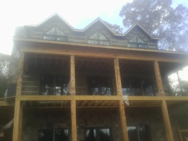 Dormers and porch framing on a large log home under construction — Roof Coating work by our crew in Blytheville