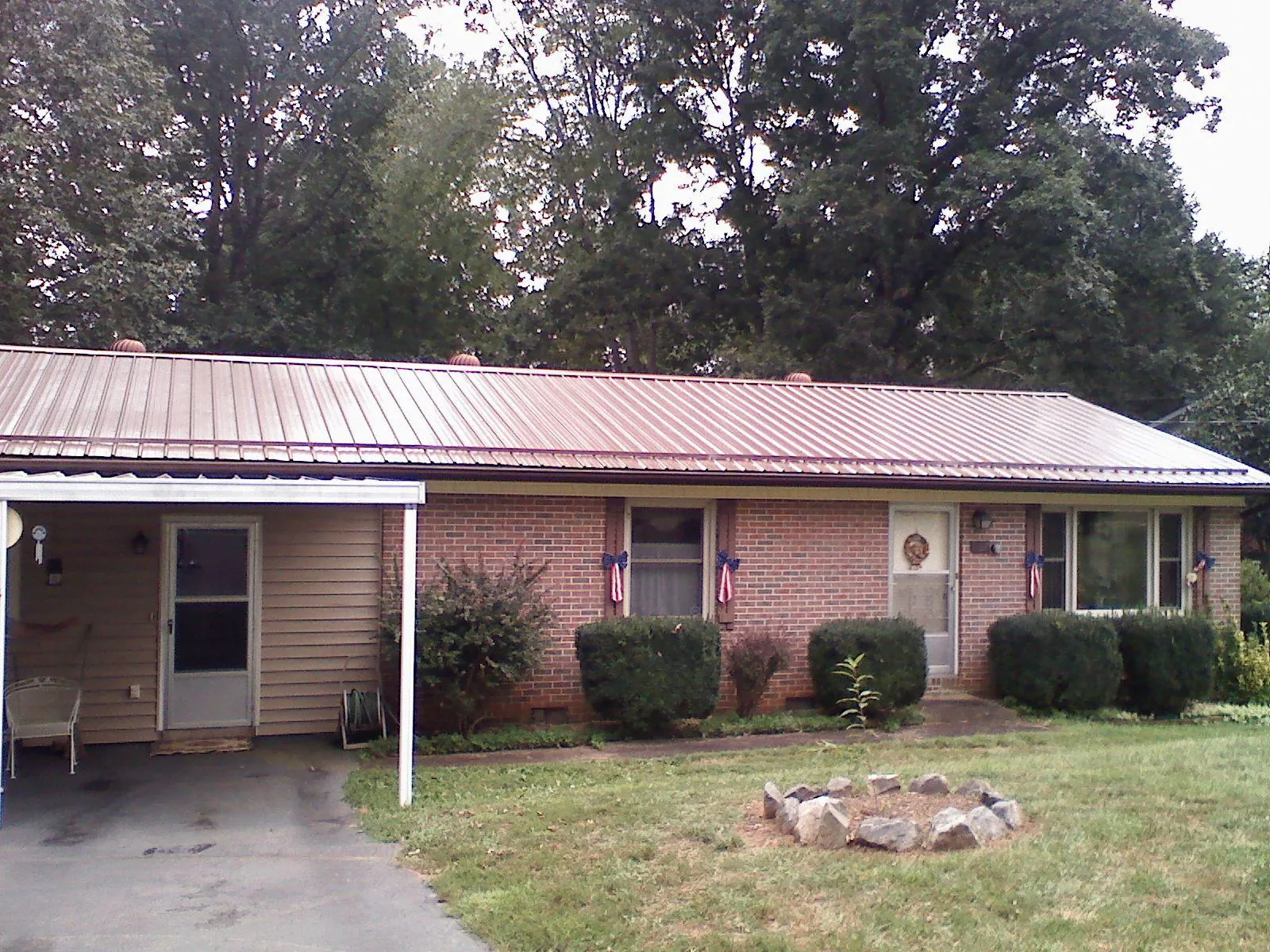 Bronze metal roof and carport on a brick ranch home — Roof Repair work by our crew in Blytheville