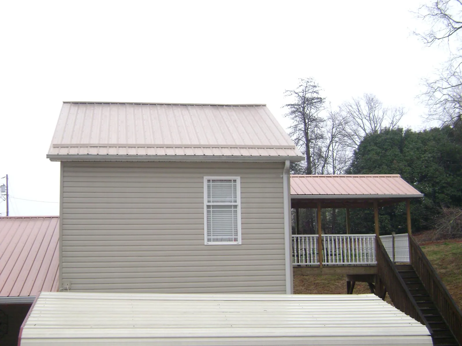 Tan metal roofs on a two story addition and attached porch, from a Roof Replacement job in Blytheville