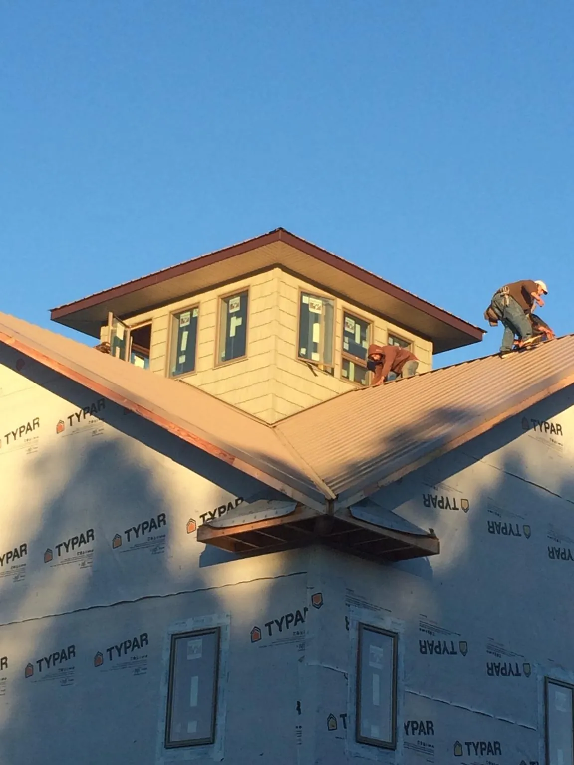 Roofers working around a rooftop cupola on a new metal roof at sunset — Roof Waterproofing in Blytheville by Roofing Brothers